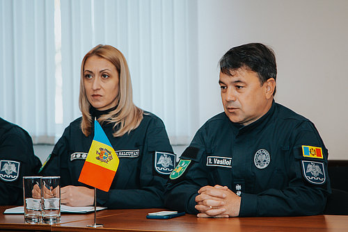 Eine Frau und ein Mann in Uniform in einer Gespr&auml;chssituation.