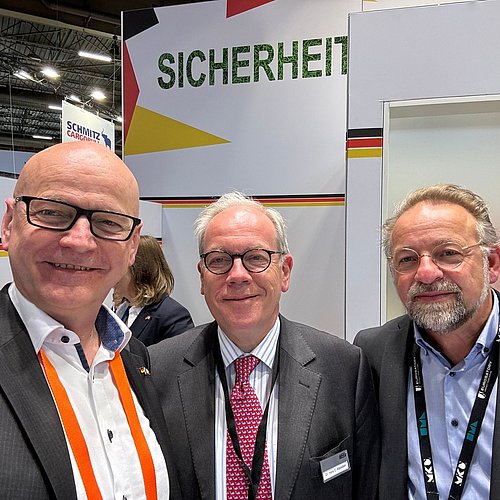 Drei Männer stehen nebeneinander und lächeln in die Kamera.