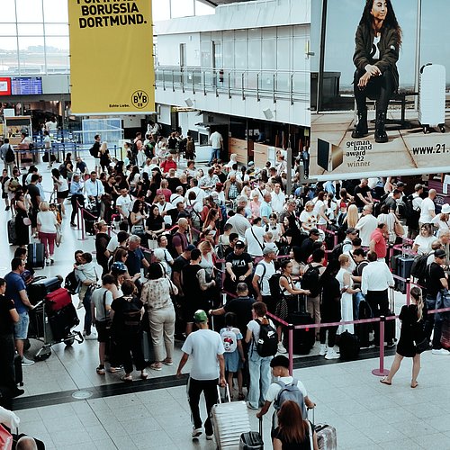 Eine Menschenmenge wartet im Flughafen auf ihren Check-In.
